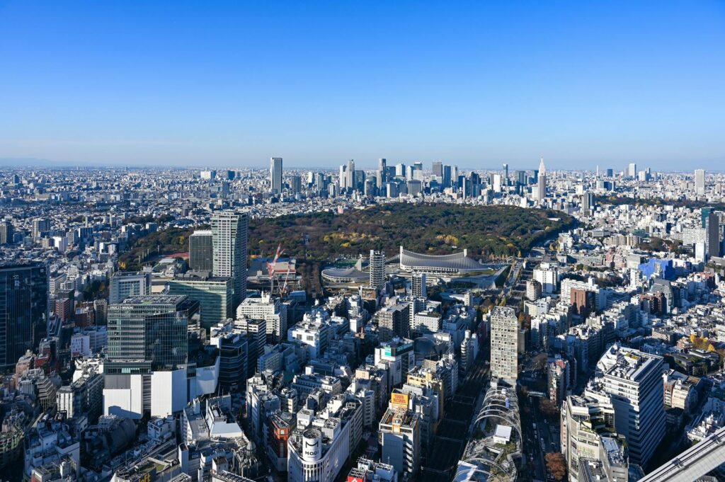 Aerial view of Tokyo cityscape featuring Shinjuku Park surrounded by skyscrapers under a clear blue sky. – foto door Laser Cheung via Pexels