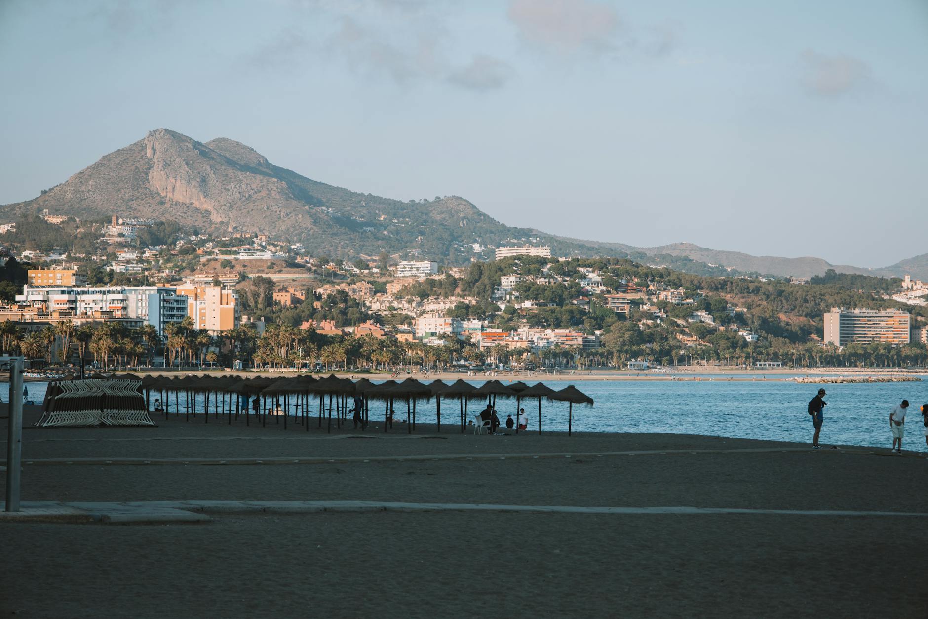 A picturesque beach scene in Málaga, Spain, featuring a mountain backdrop and people enjoying the sandy shore. – foto door Joaquin Carfagna via Pexels